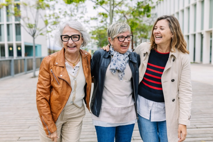 three women walk outside and laugh together